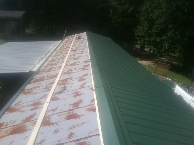 Old rusted panels beside newly installed green metal roofing — Wind Damage Roof Repair by Roofing Brothers in Albion