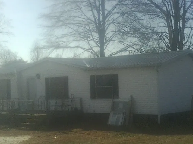 New metal roof on a white painted brick home on a foggy morning in Albion